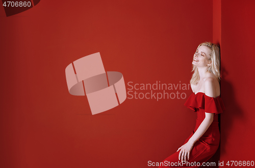 Image of Beautiful young adult woman wearing red jumpsuit standing next t