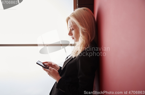 Image of Young adult woman using smartphone at the office