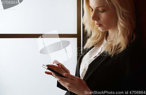 Image of Young adult woman using smartphone at the office