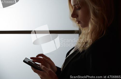 Image of Young adult woman using smartphone at the office