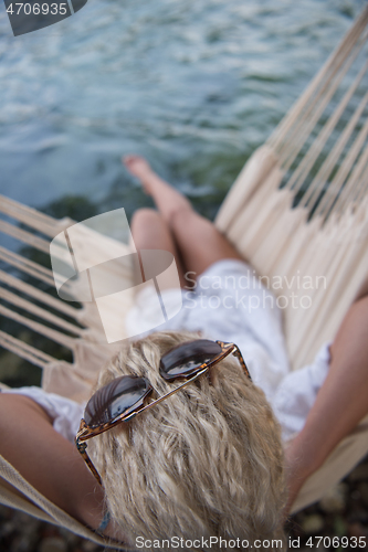 Image of blonde woman resting on hammock