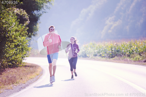 Image of young couple jogging along a country road