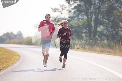 Image of young couple jogging along a country road