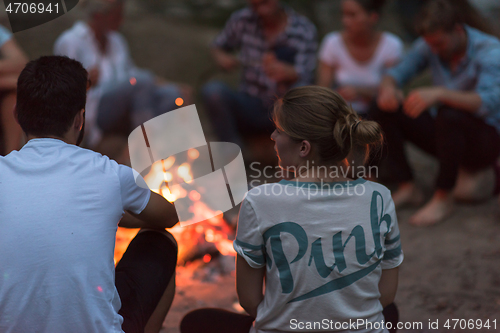 Image of young friends relaxing around campfire