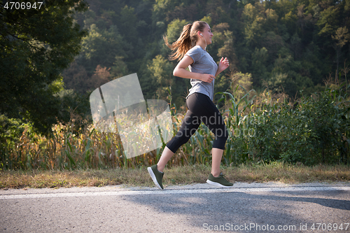 Image of woman jogging along a country road