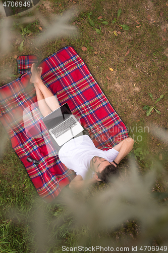 Image of top view of man using a laptop computer under the tree