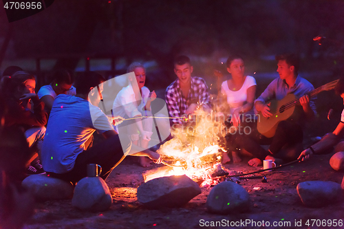 Image of young friends relaxing around campfire