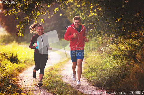 Image of young couple jogging along a country road