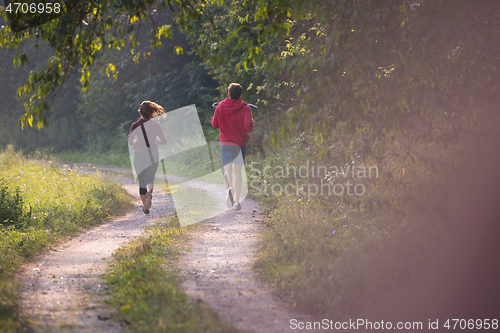 Image of young couple jogging along a country road