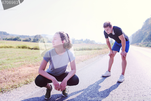 Image of young couple warming up and stretching on a country road