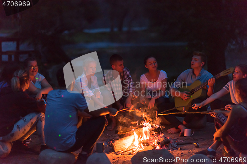 Image of young friends relaxing around campfire