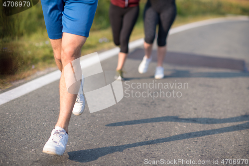 Image of young people jogging on country road