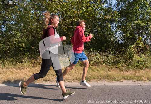 Image of young couple jogging along a country road