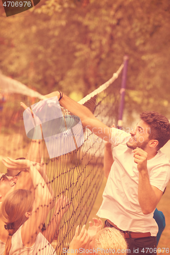 Image of group of young friends playing Beach volleyball