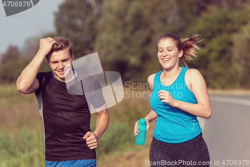 Image of young couple jogging along a country road