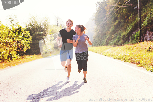 Image of young couple jogging along a country road