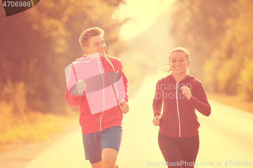 Image of young couple jogging along a country road