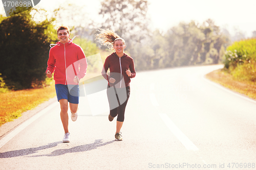 Image of young couple jogging along a country road