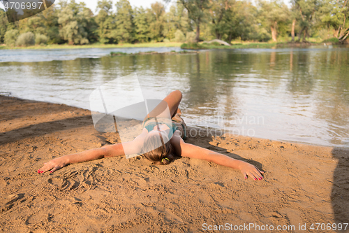 Image of girl in a green bikini relaxing on the riverbank