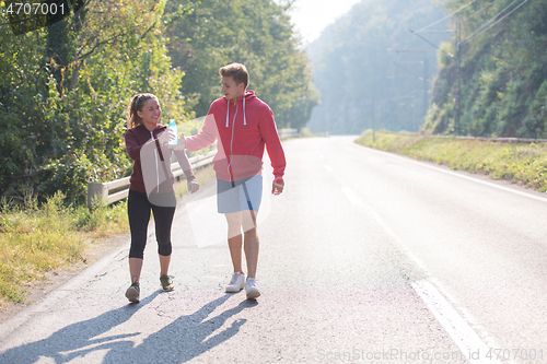 Image of young couple jogging along a country road