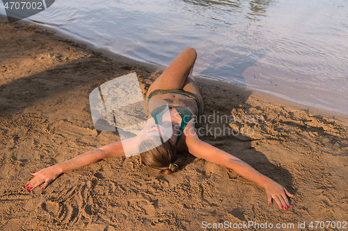 Image of girl in a green bikini relaxing on the riverbank