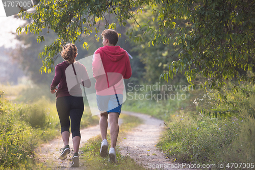 Image of young couple jogging along a country road