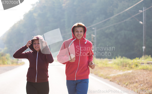 Image of young couple jogging along a country road