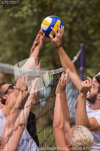 Image of group of young friends playing Beach volleyball