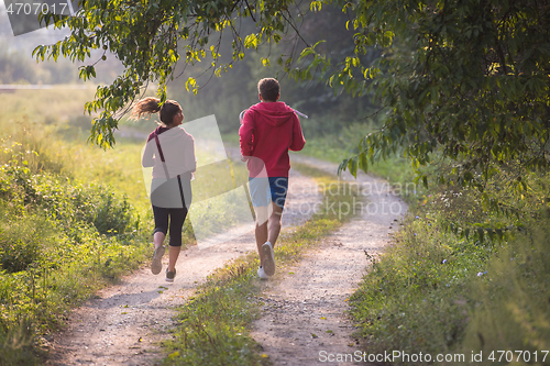 Image of young couple jogging along a country road