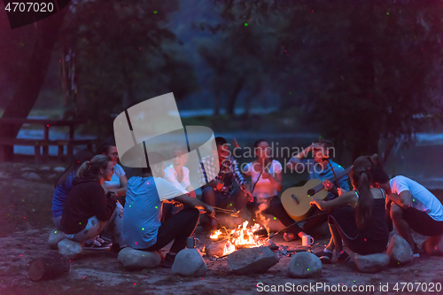 Image of young friends relaxing around campfire