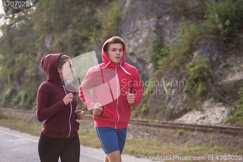 Image of young couple jogging along a country road