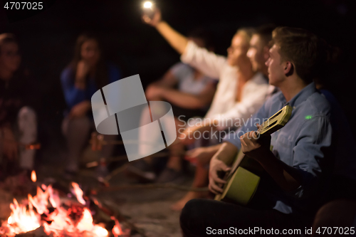 Image of young friends relaxing around campfire