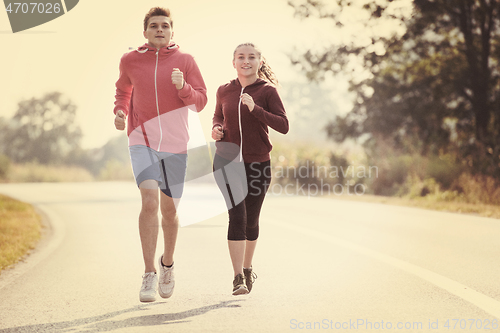 Image of young couple jogging along a country road