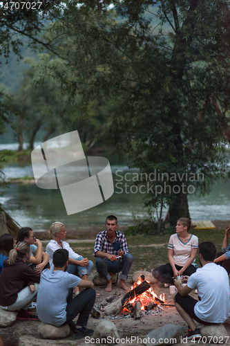 Image of young friends relaxing around campfire