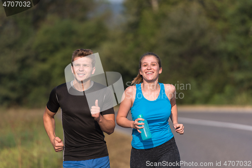 Image of young couple jogging along a country road