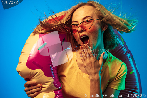 Image of Beautiful woman in neon light isolated on blue studio background