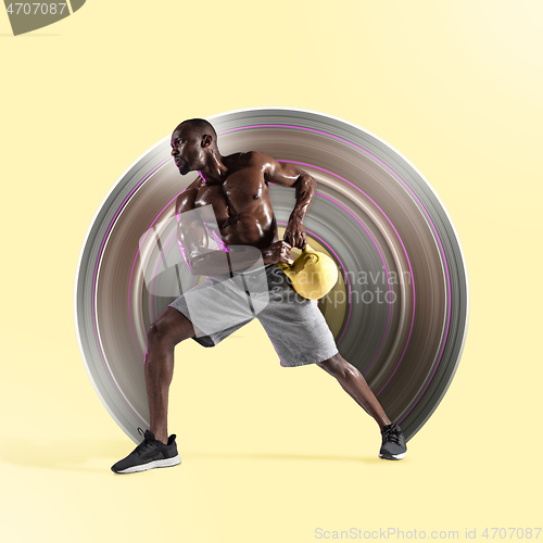 Image of Young african-american bodybuilder training over yellow background