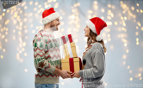 Image of happy couple in christmas sweaters with gifts