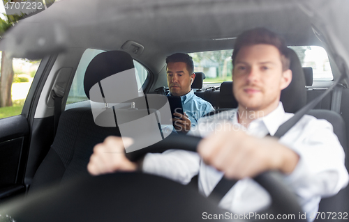 Image of man with tablet pc and earphones riding in car