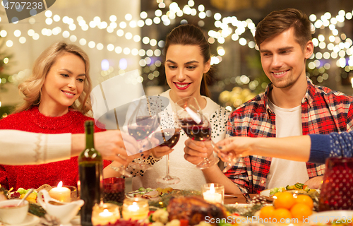 Image of happy friends drinking red wine at christmas party