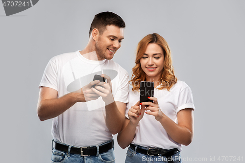 Image of happy couple in white t-shirts with smartphones