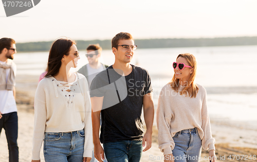 Image of happy friends walking along summer beach