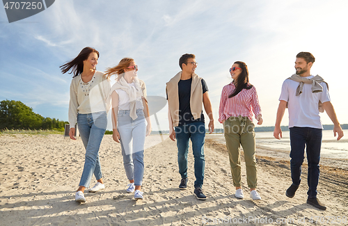 Image of happy friends walking along summer beach