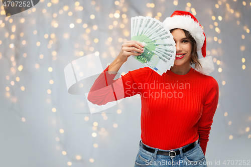 Image of happy woman in santa hat with money on christmas