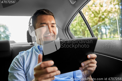 Image of passenger with headphones using tablet pc in car