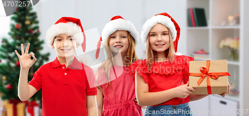 Image of children in santa helper hats with christmas gift