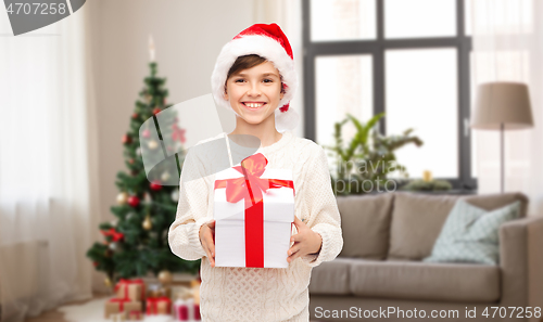 Image of happy boy in santa hat with christmas gift at home