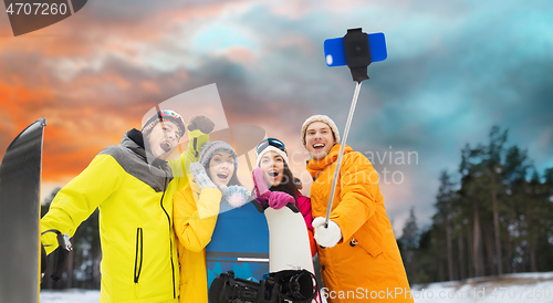 Image of happy friends with snowboards and smartphone