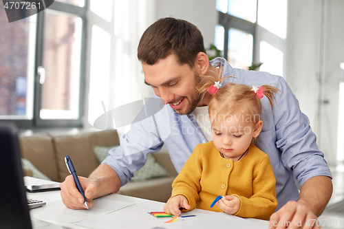 Image of working father with baby daughter at home office