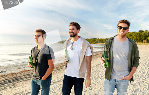 Image of young men with non alcoholic beer walking on beach